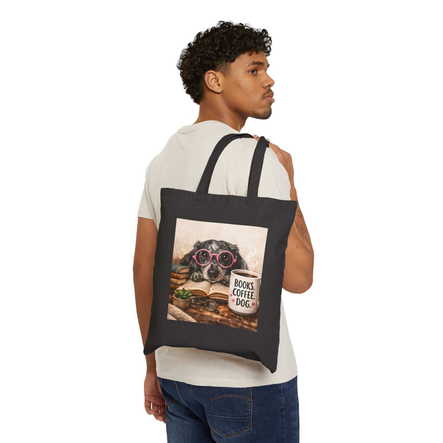 Man carrying a black tote bag with a dog design featuring a book and coffee cup.
